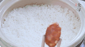 煮开后转小火，当米饭出现小孔时，铺上金字麻辣香肠。