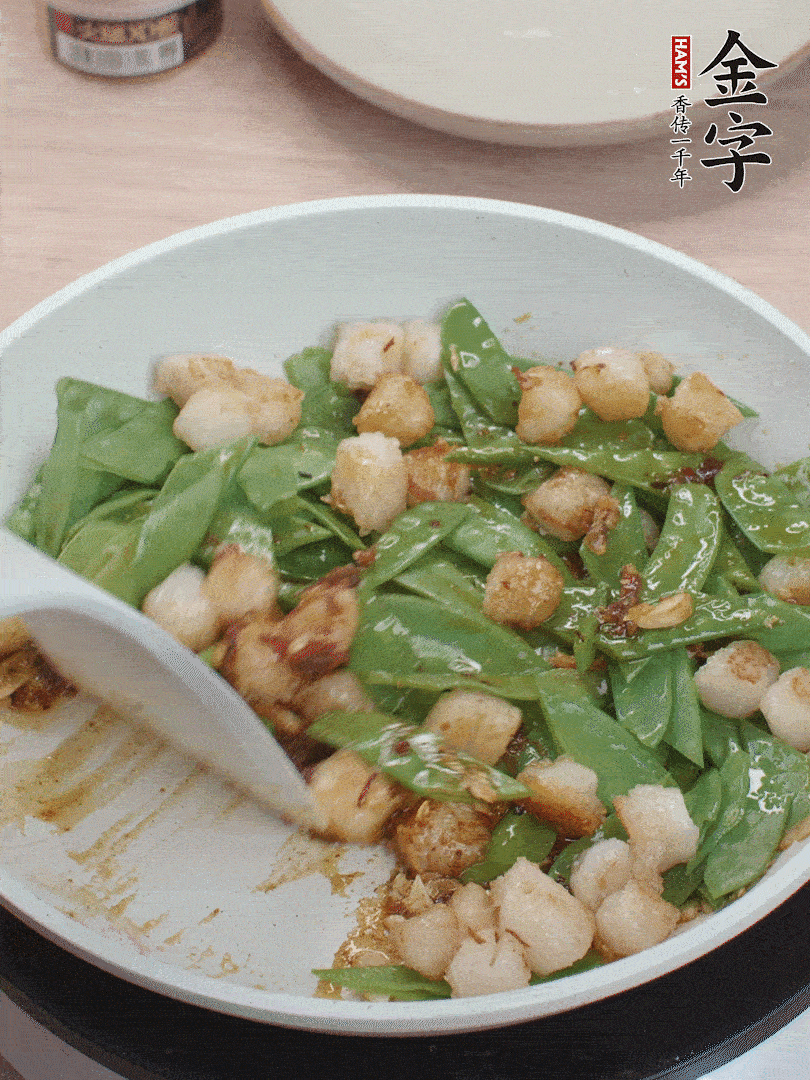 下甜豆荚、鲜贝轻轻翻炒均匀。